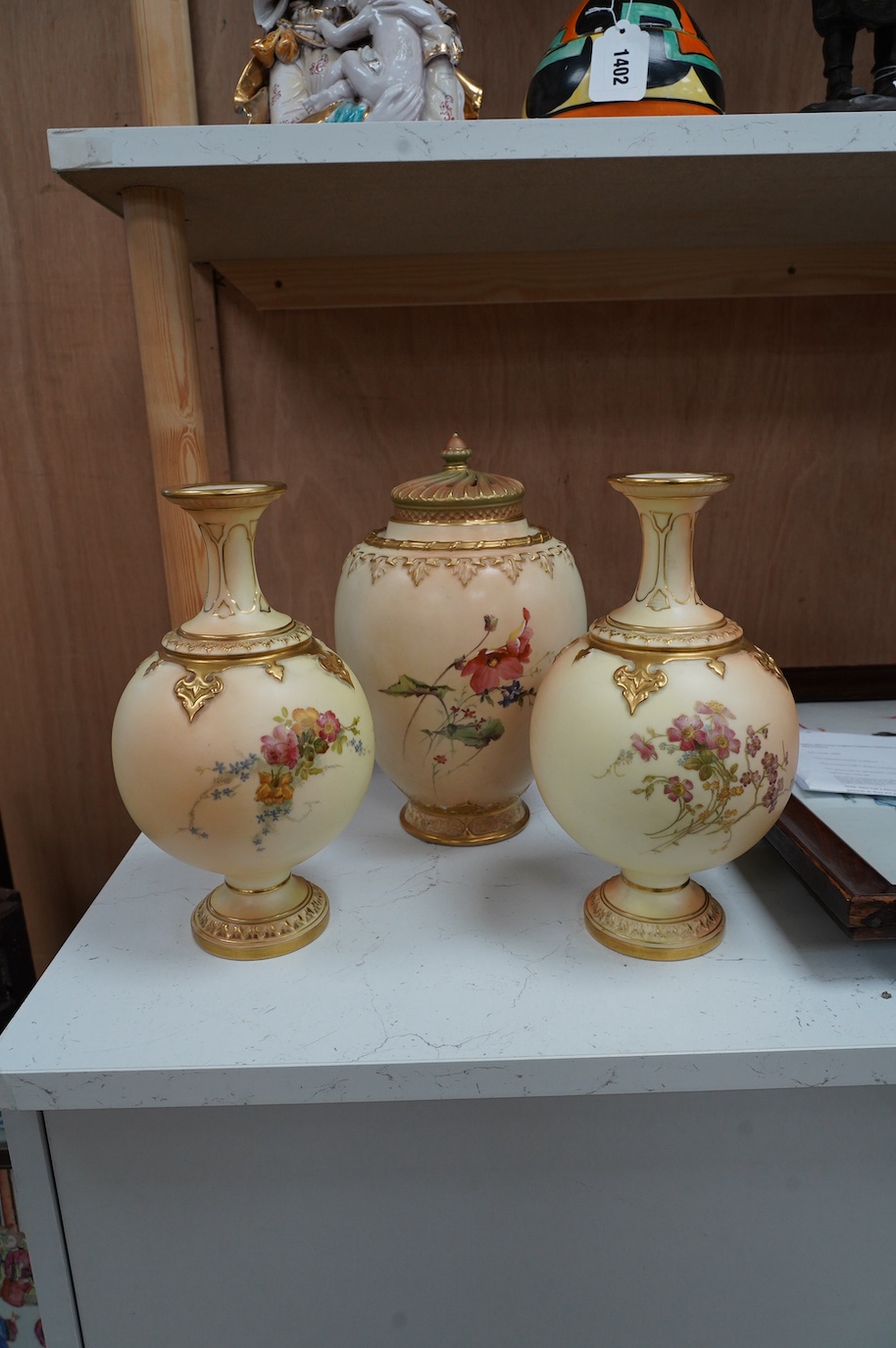 A Worcester blush ivory jar and cover, and a pair of similar vases, shape numbers 2048 and 1851, tallest 26cm. Condition - good